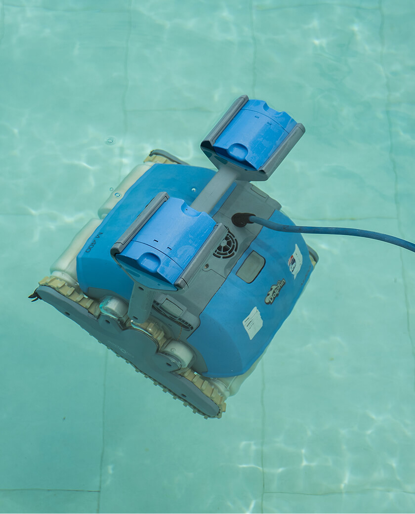 A robotic pool cleaner working on the floor of a pool, seen from above